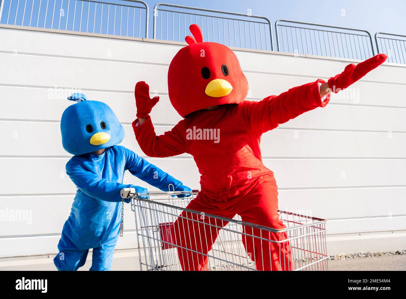 Woman wearing red duck costume standing in shopping cart Stock Photo