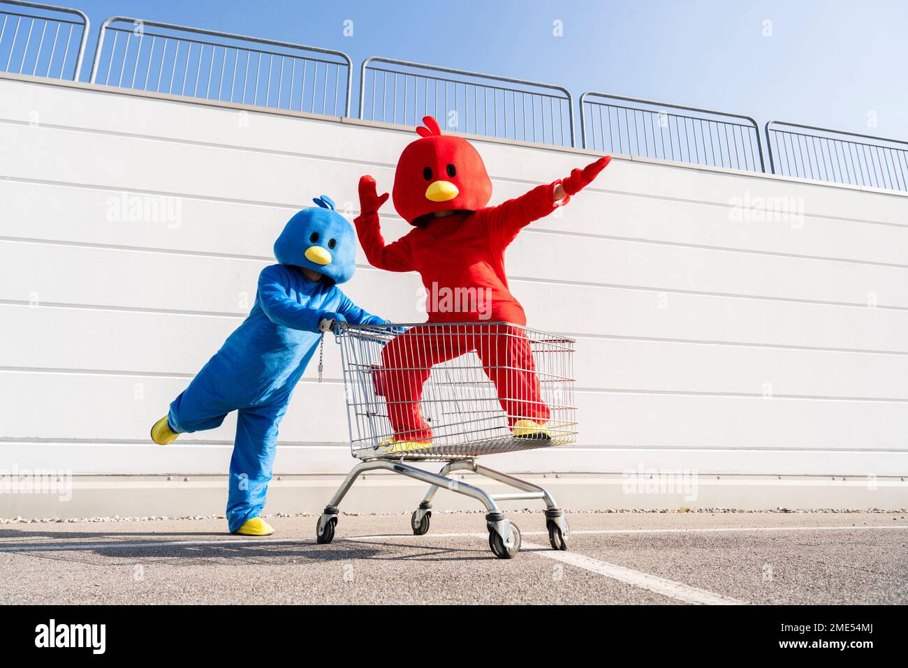 Woman wearing red duck costume having fun with man pushing shopping cart Stock Photo