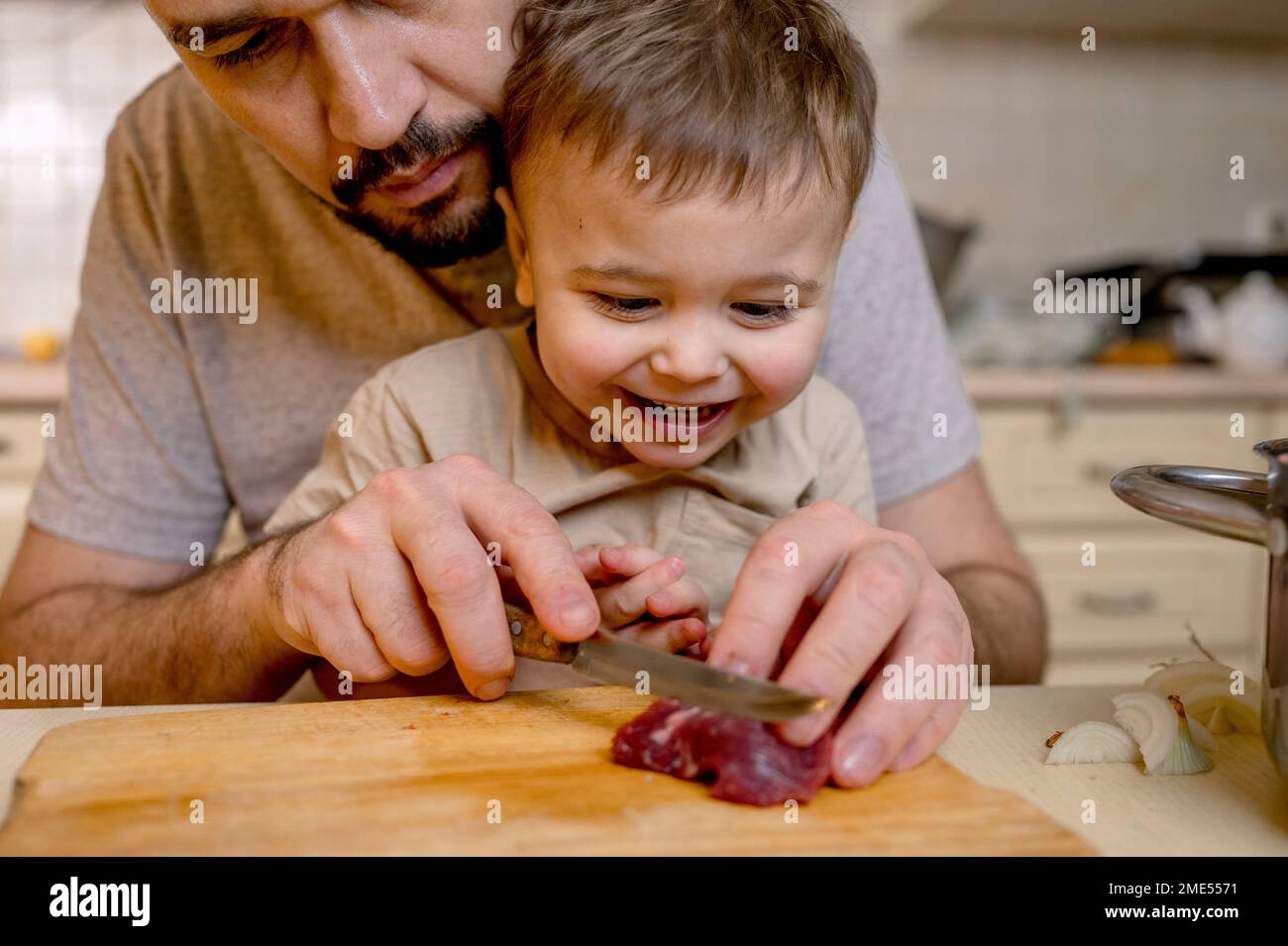 Father cutting red meat with son in kitchen Stock Photo - Alamy
