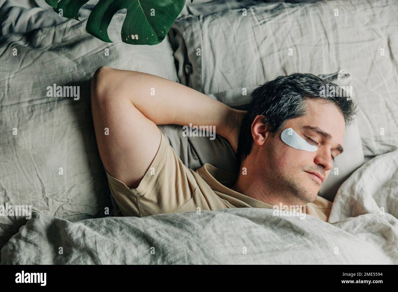 Man with under eye patches sleeping in bedroom Stock Photo Alamy
