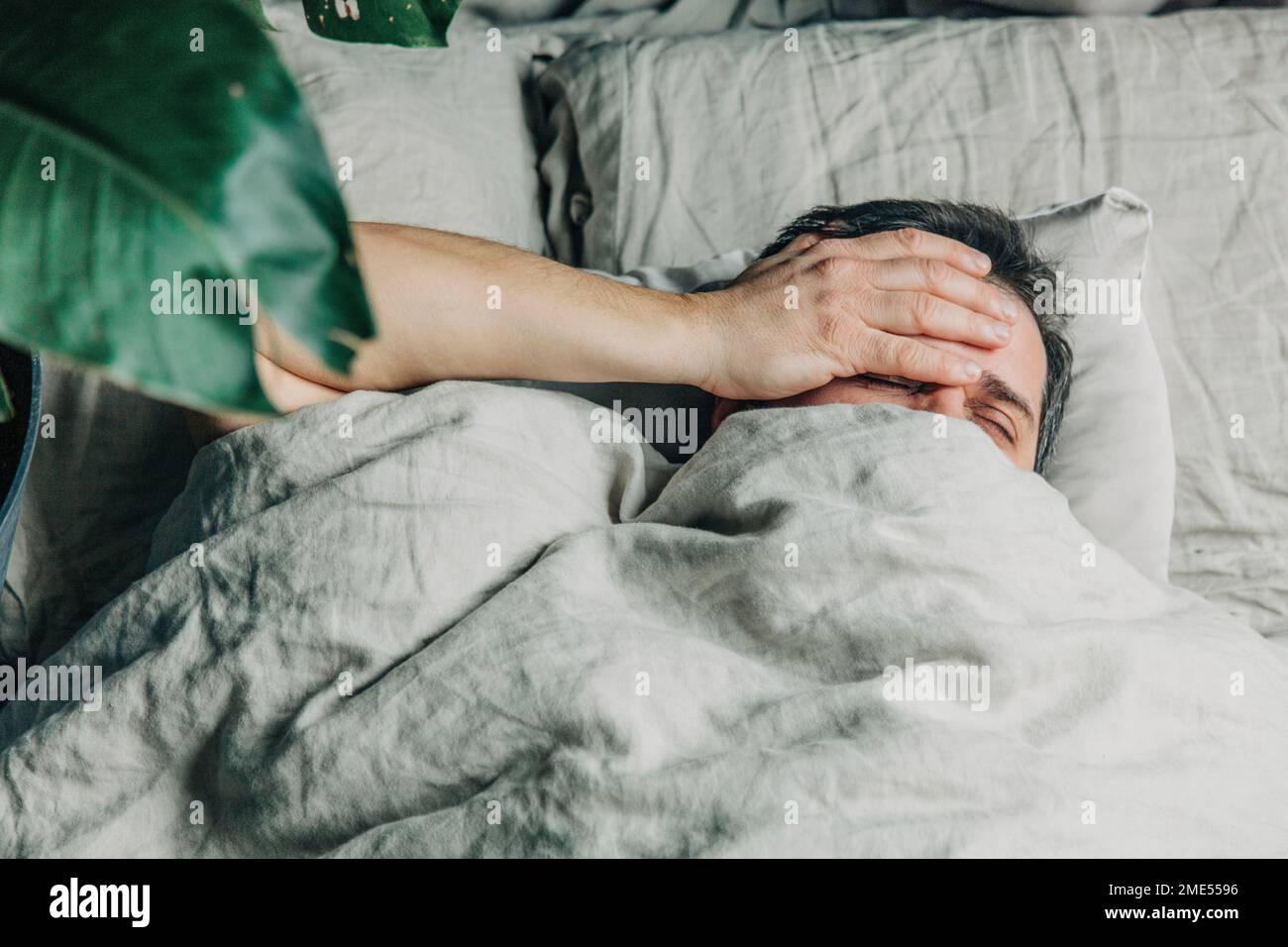 Man with hand on head lying in bed Stock Photo Alamy