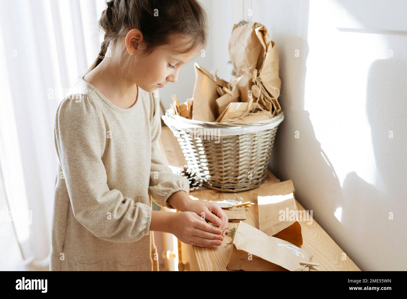 Cute girl opening gifts on cabinet at home Stock Photo