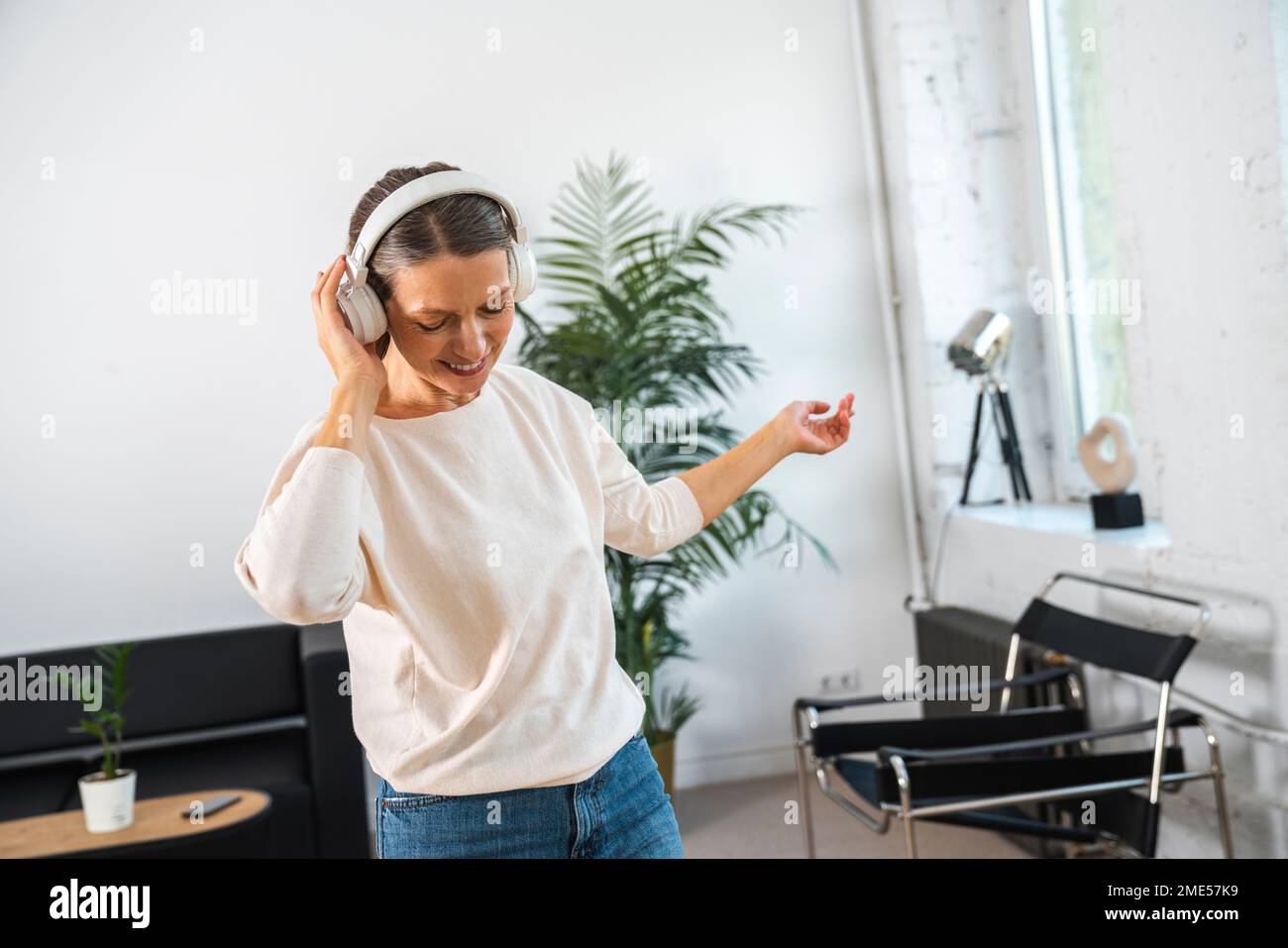 Businesswoman wearing wireless headphones enjoying in office Stock ...