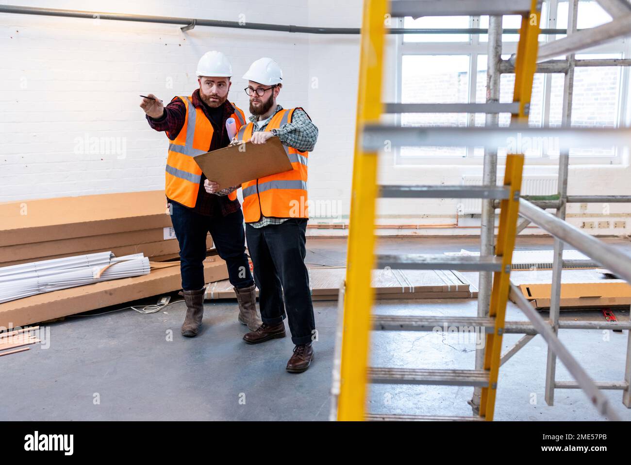 Young engineers examining and discussing over document at construction site Stock Photo