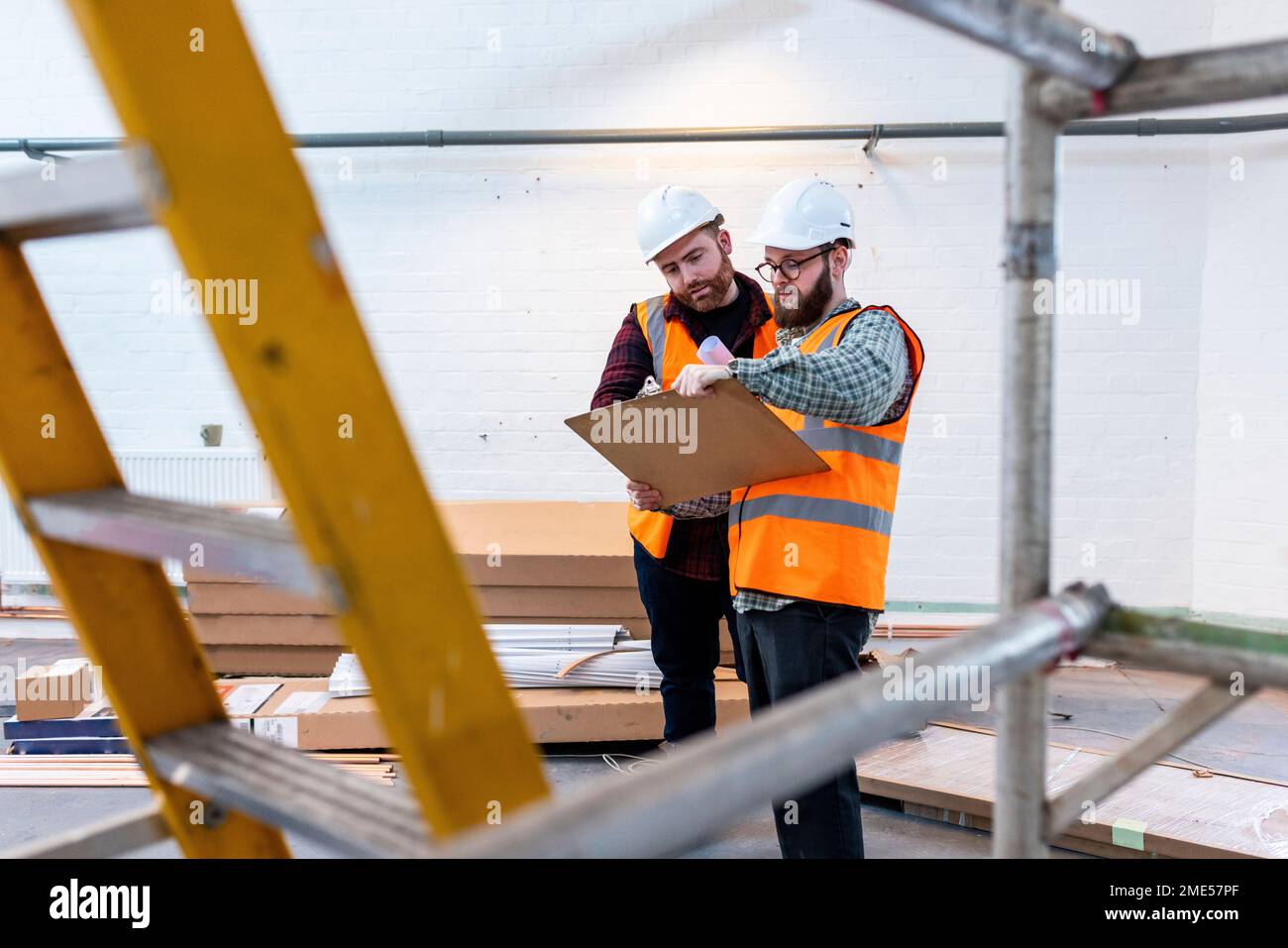Engineers wearing hardhats having discussion over document Stock Photo