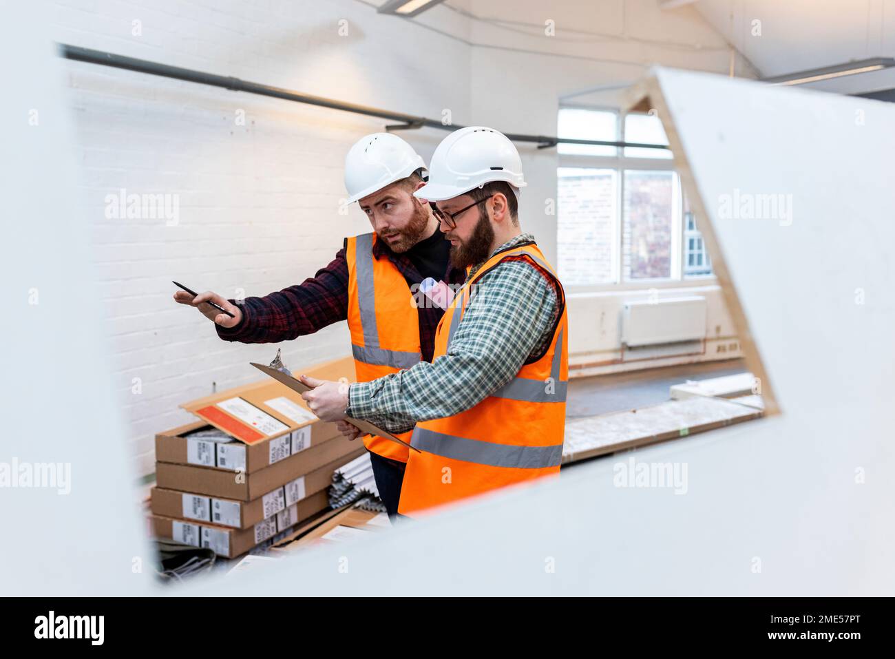 Engineers examining and discussing over document at construction site Stock Photo