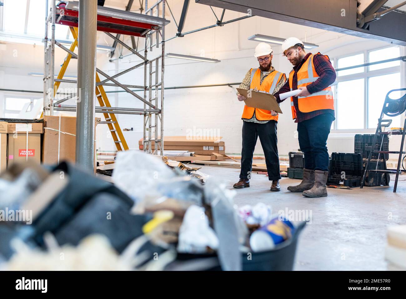 Young engineers having discussion over document at construction site Stock Photo