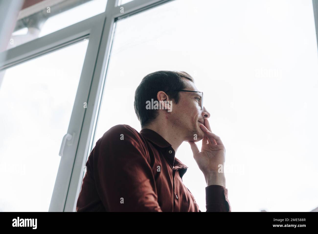 Thoughtful businessman looking through window Stock Photo