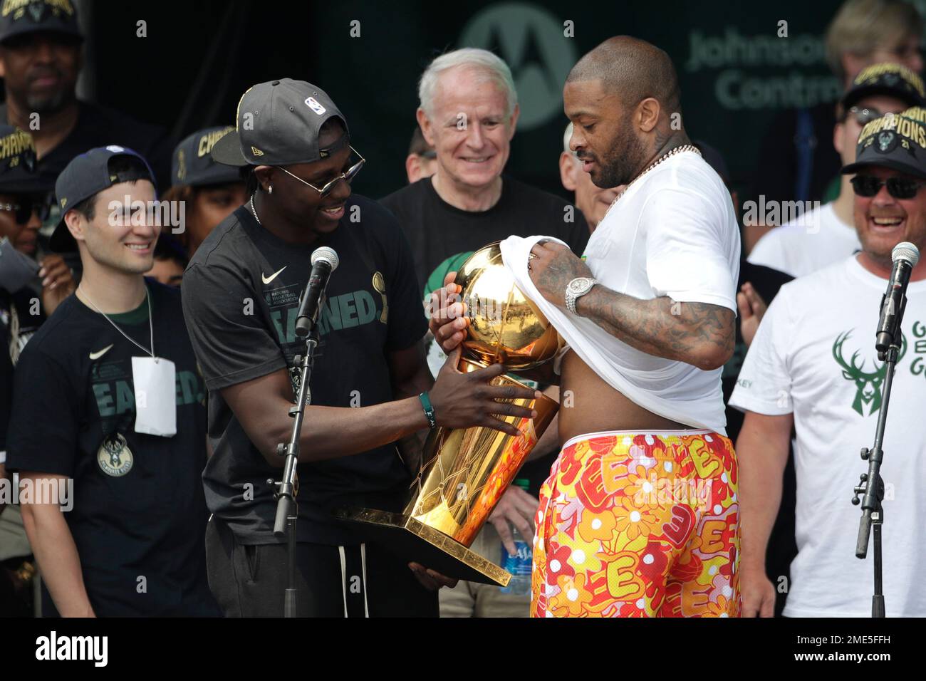 Milwaukee Bucks' P.J. Tucker, right, wipes champagne off the NBA Championship trophy with Jrue