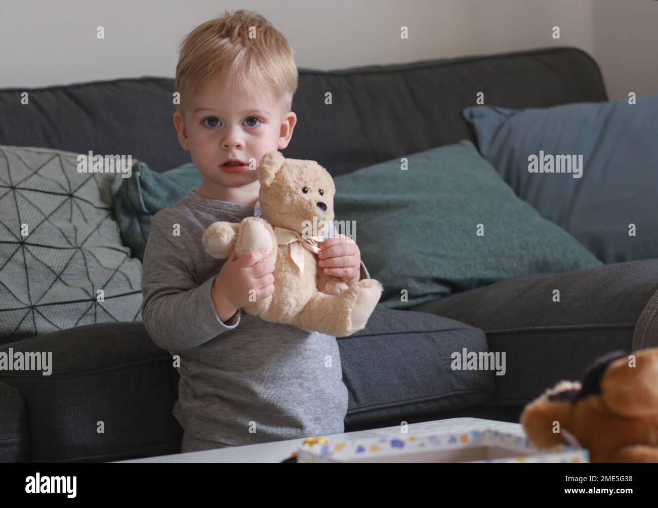 portrait of cute happy little boy playing with teddy bear in living ...