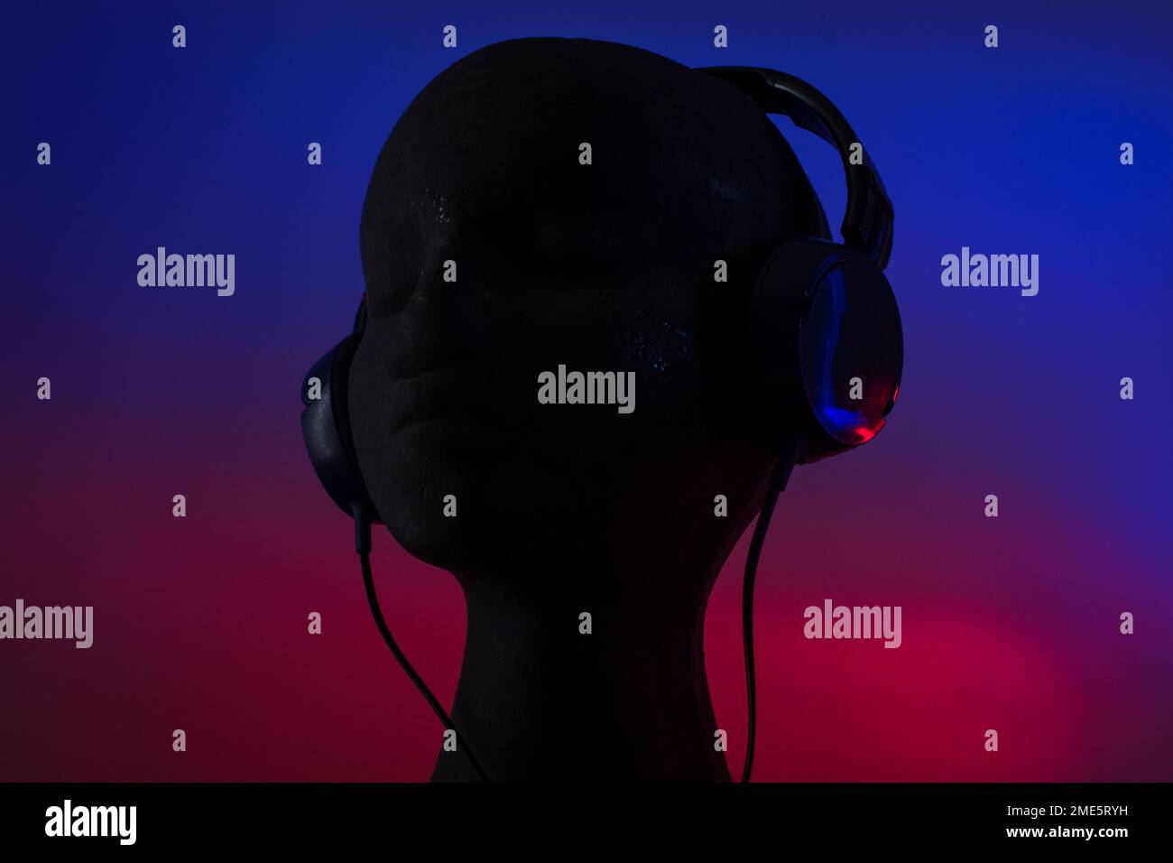 Over-ear headphones on black head on blue and red background Stock Photo