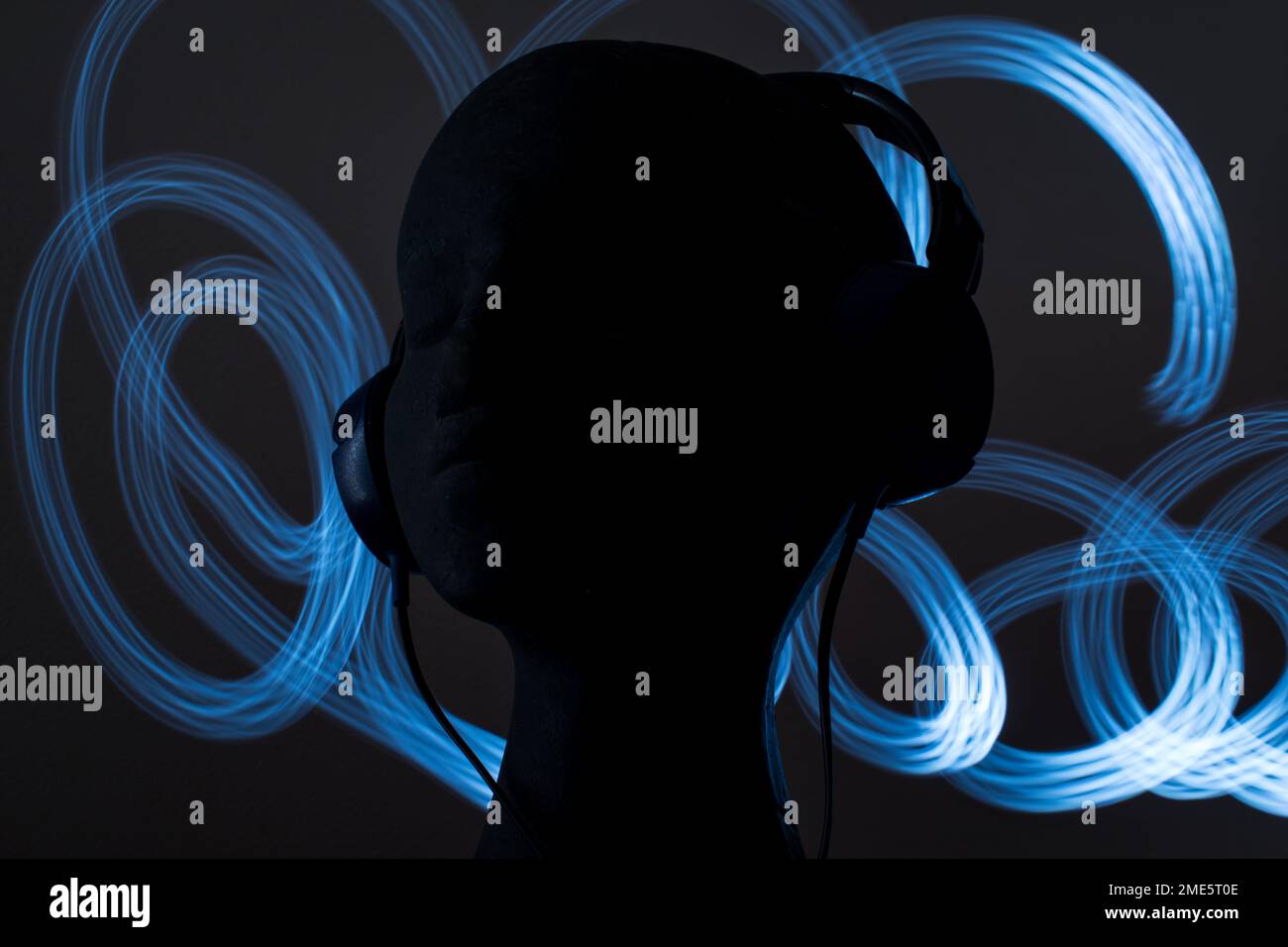 Blue over-ear headphones on black head on black background Stock Photo
