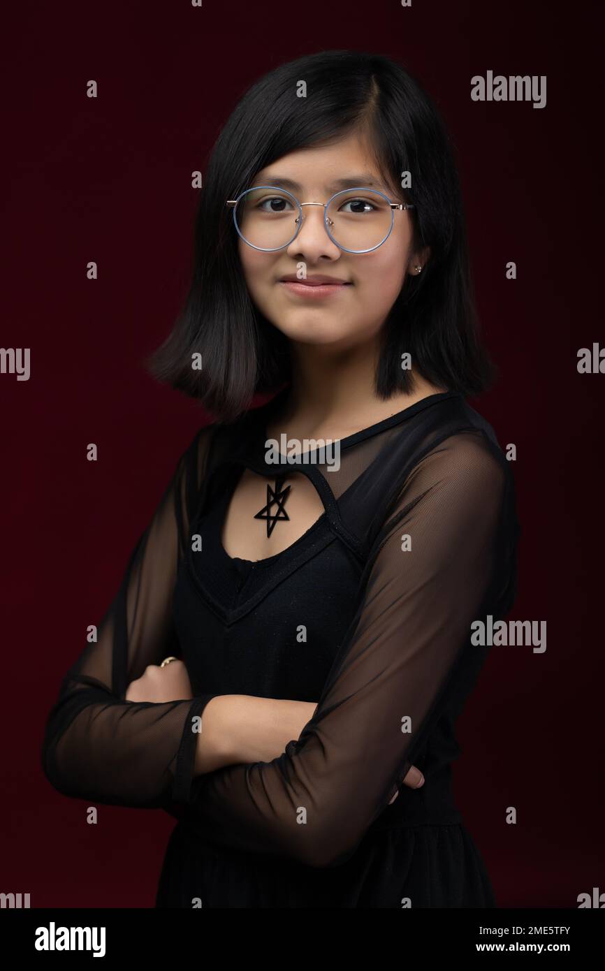 12 year old girl portrait isolated on red background wearing gla Stock