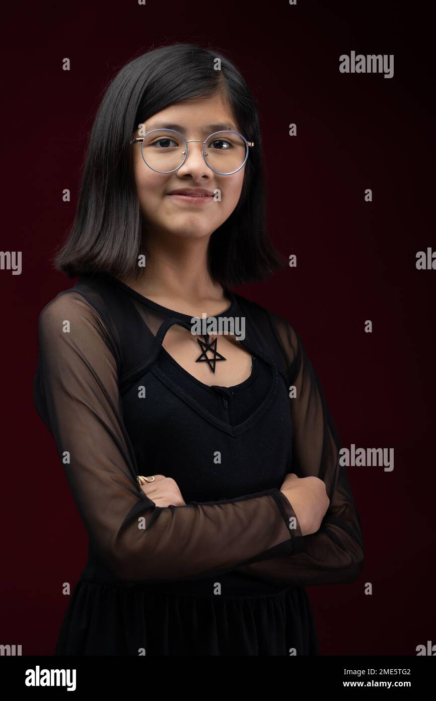 12 year old girl portrait isolated on red background wearing glasses Stock Photo
