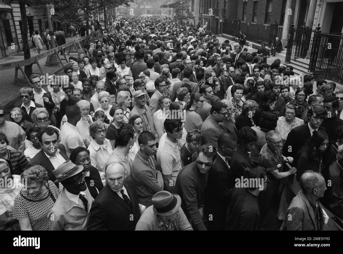 Thousands of persons wait behind police barriers outside the Frank E. Campbell funeral home on