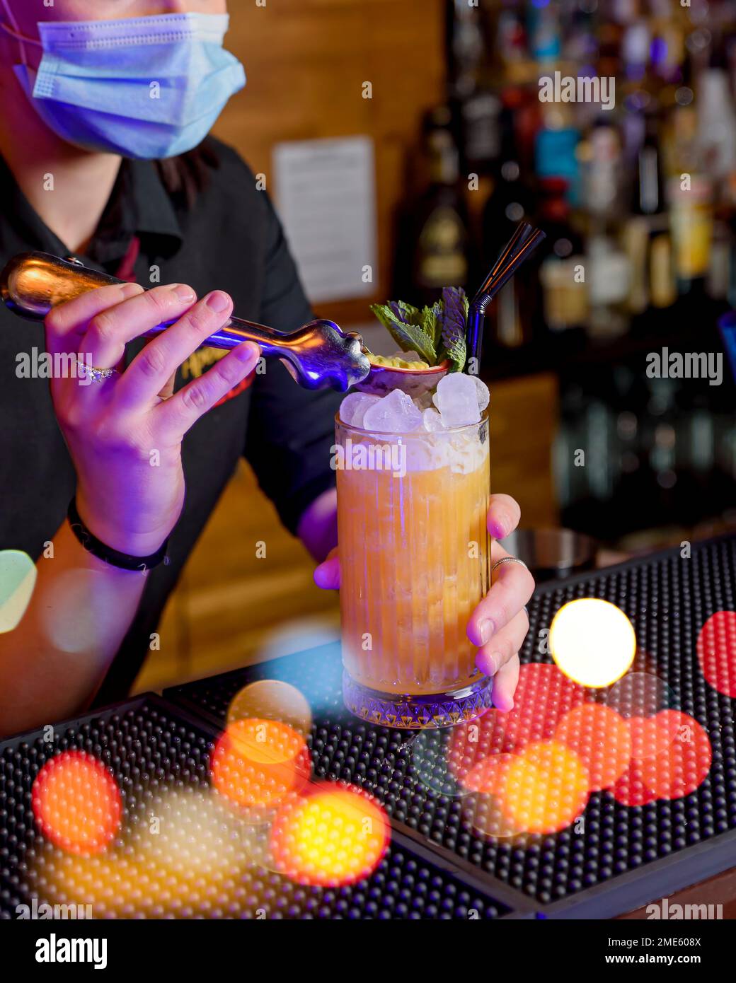 young girl with mask preparing cocktail in a crystal glass. barman concept Stock Photo