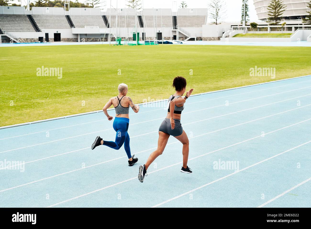 Competition is necessary. Full length shot of two attractive young athletes running a track field together during an outdoor workout session. Stock Photo
