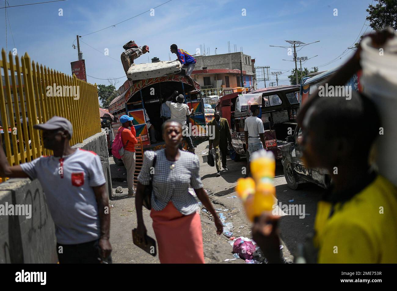 Locals load a mattress on the roof of a bus at the PetionVille market