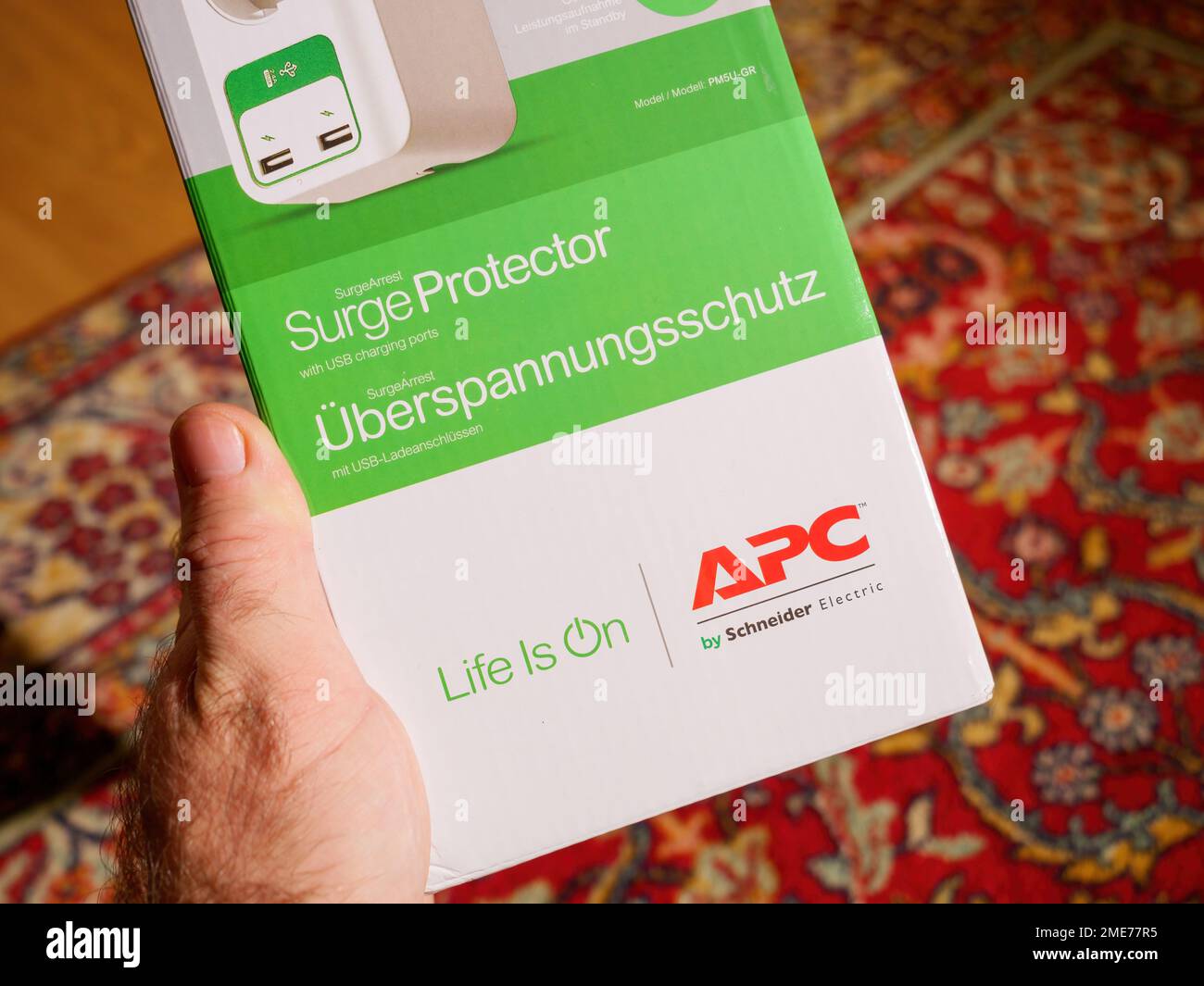 Frankfurt, Germany - Dec 2, 2022: POV male customer hand holding APC American Power Conversion Corporation by Schneider Electric cardboard package with Life is on slogan Stock Photo