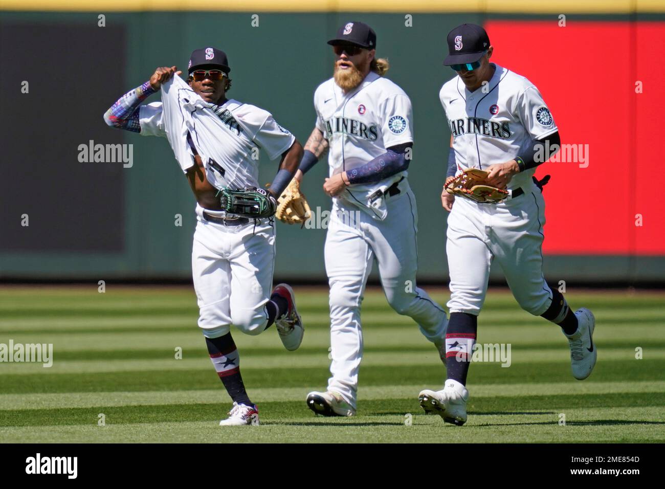 Seattle Mariners' Shed Long Jr., left, tugs on his jersey as he leads  fellow outfielders Jake Fraley and Jake Bauers off the field after the team  beat the Texas Rangers in a