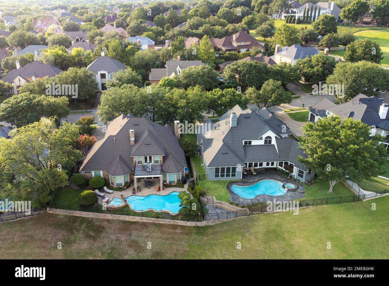 Aerial drone view of luxury mansions with swimming pools surrounded by ...