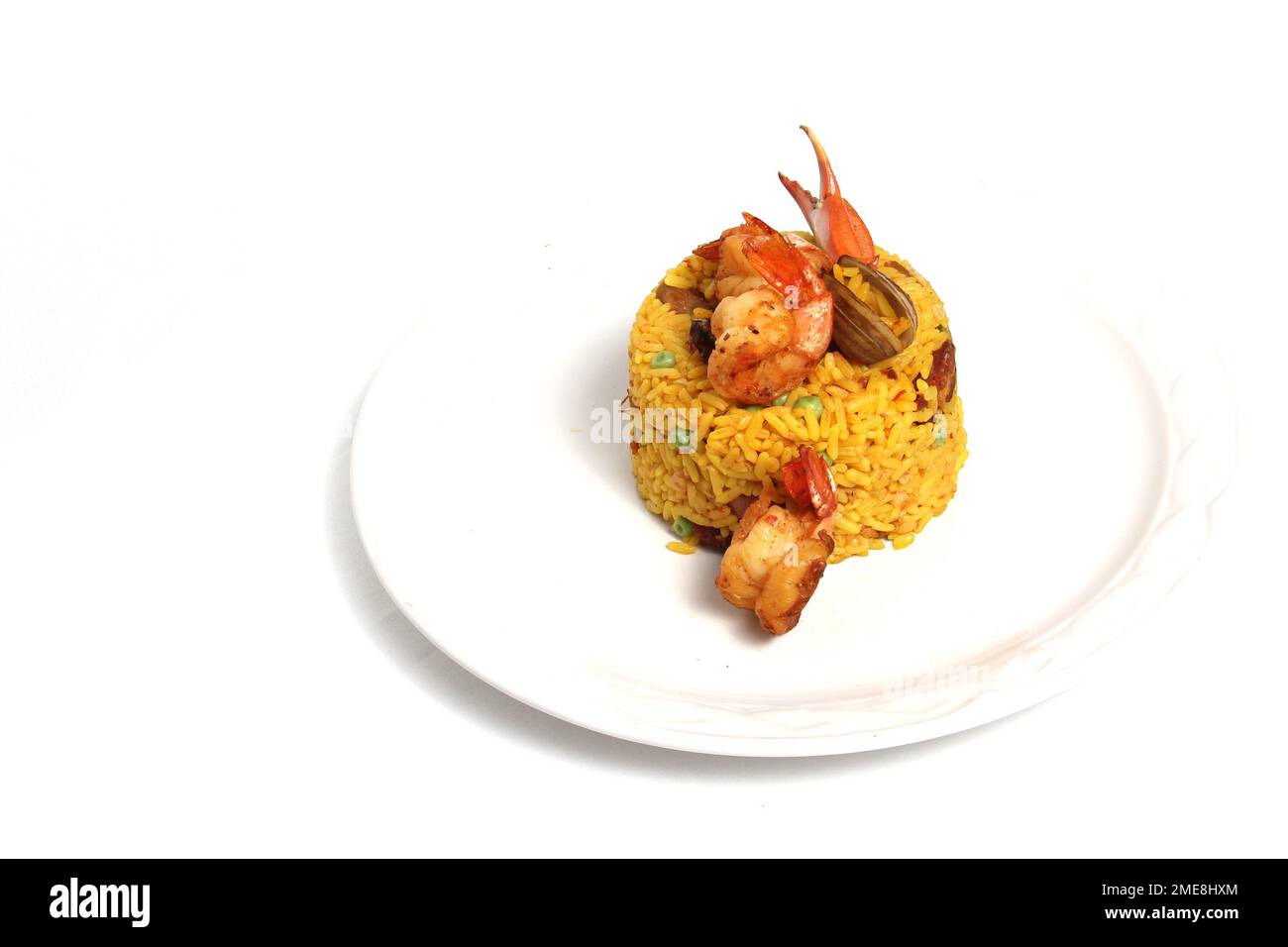 Paella rice is a traditional cuisine recipe from the city of Valencia Spain prepared with saffron, seafood, shrimp, vegetables served on a white plate Stock Photo