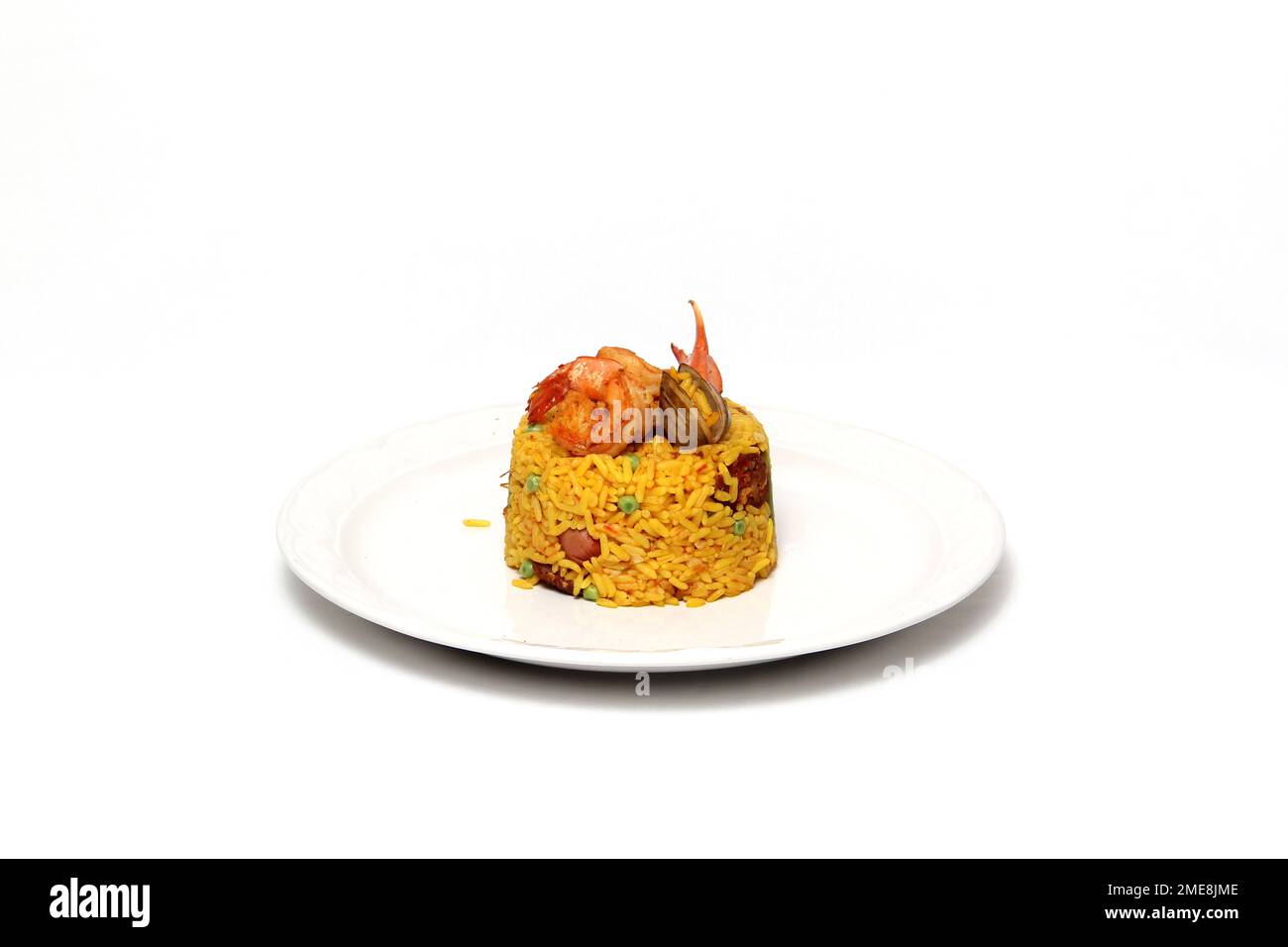 Paella rice is a traditional cuisine recipe from the city of Valencia Spain prepared with saffron, seafood, shrimp, vegetables served on a white plate Stock Photo