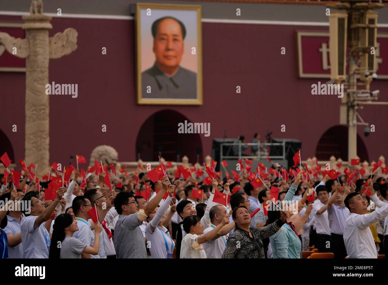 People wave Chinese flags beneath a large portrait of the late leader