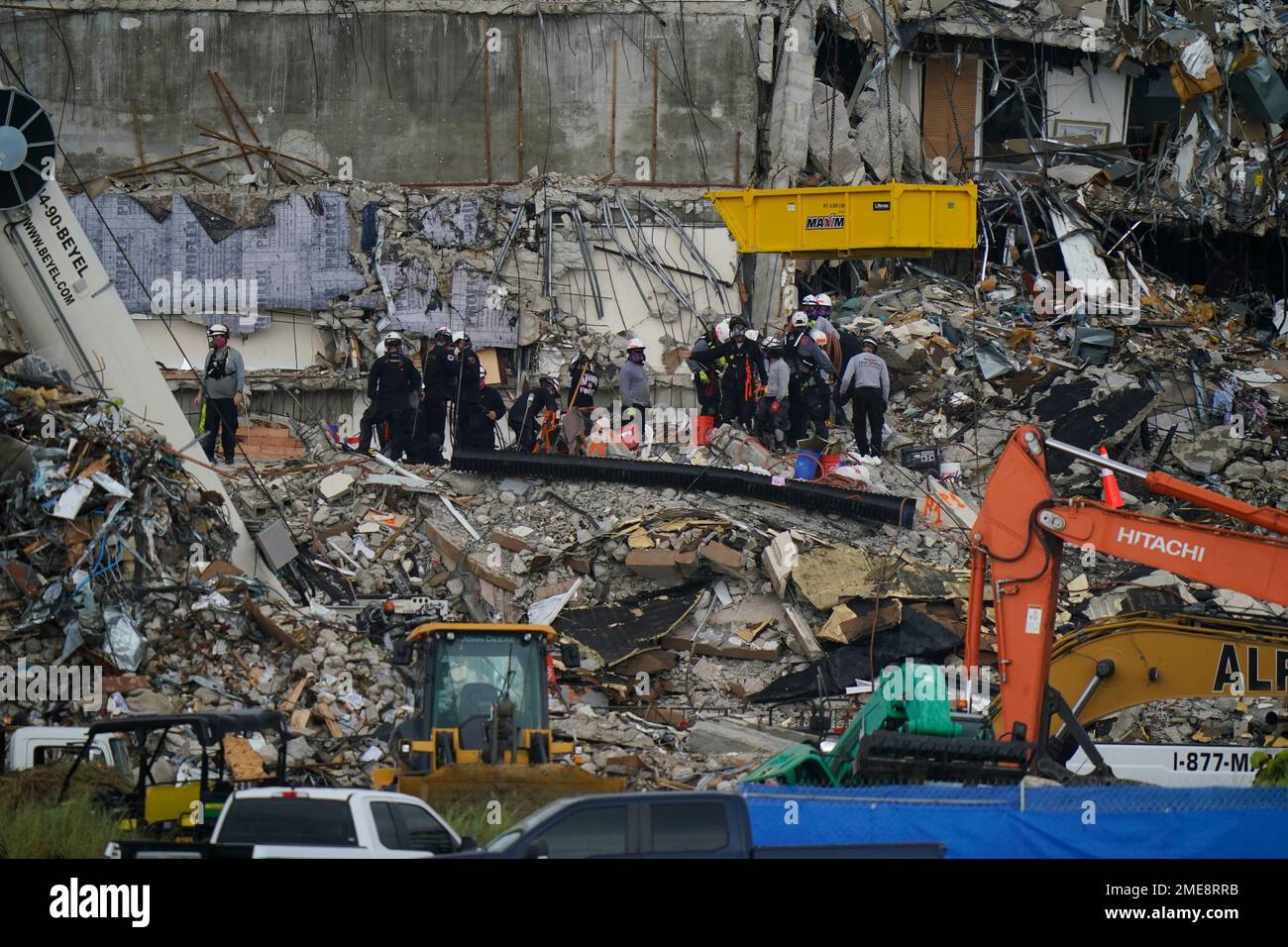 Search and rescue personnel work alongside heavy machinery to sift ...