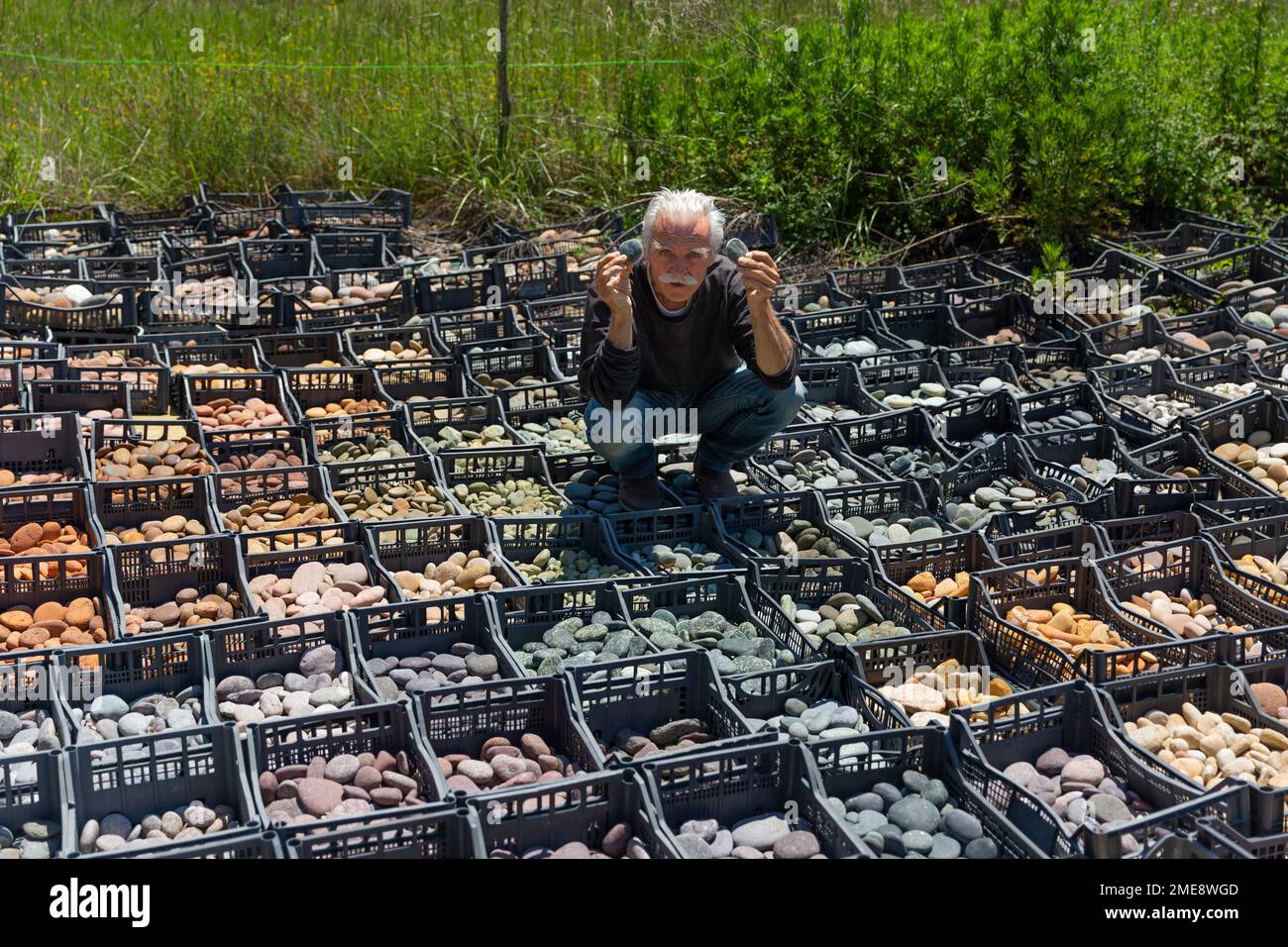 German sculptor Deva Manfred with collection of coloured stones used to create his art in Dreamwoods Park, hidden in the hills of Tuscany, Italy. Stock Photo