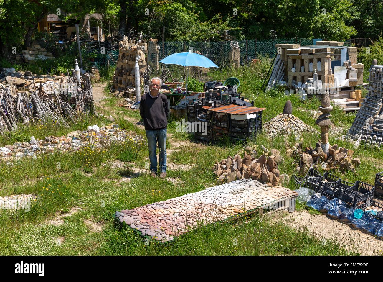 German sculptor Deva Manfred with collection of coloured stones used to create his art in Dreamwoods Park, hidden in the hills of Tuscany, Italy. Stock Photo