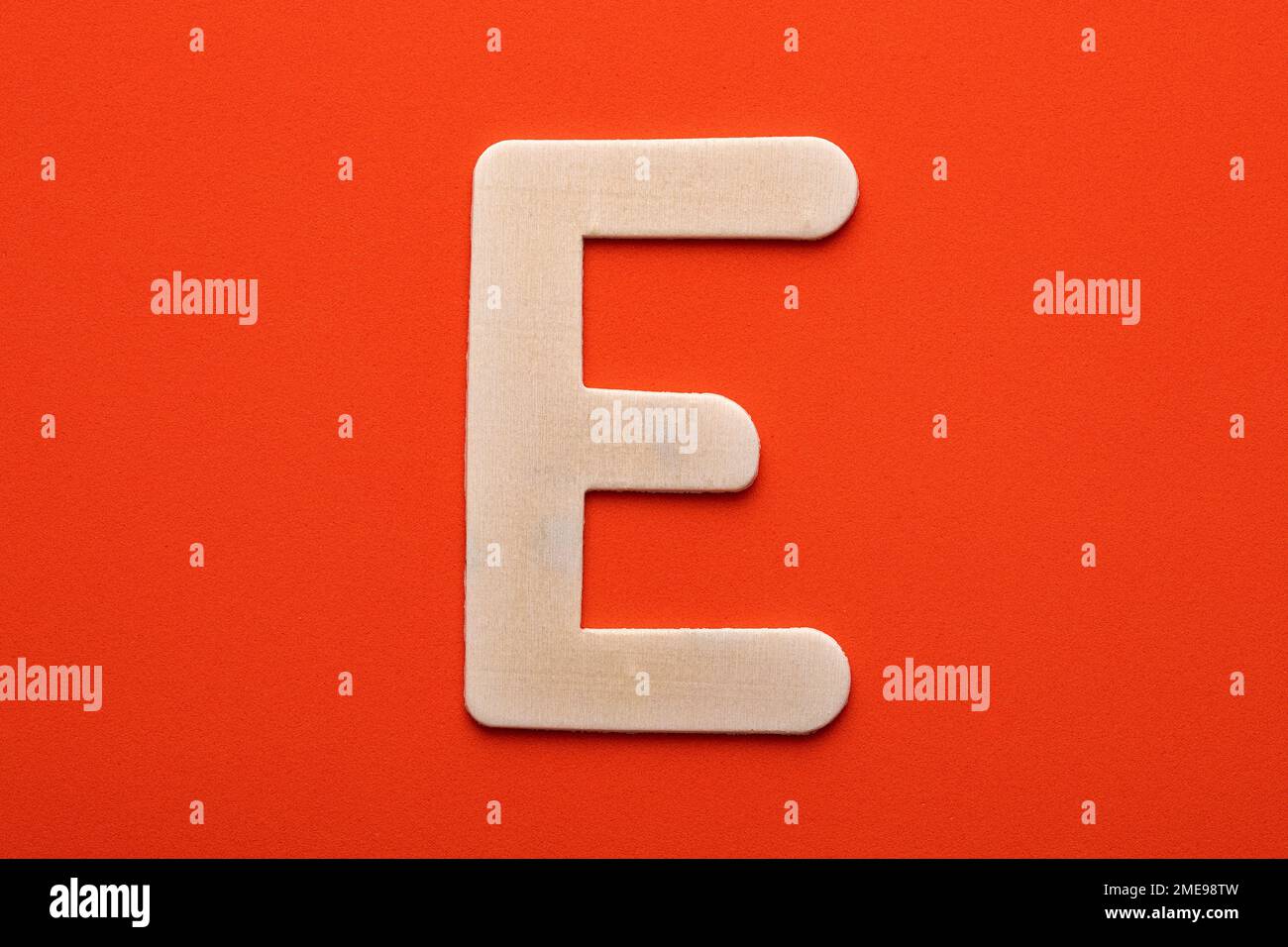 Alphabet letter E - White wood piece on orange foamy background Stock ...