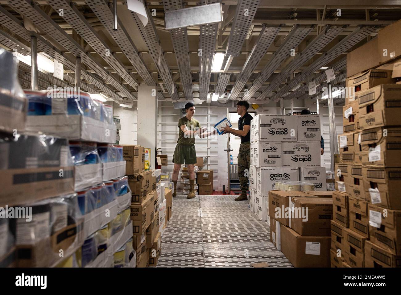 U.S. Marines with Battalion Landing Team 2/5, 31st Marine Expeditionary Unit, pass a box in the store room during a replenishment at sea aboard USS New Orleans (LPD 18) in the Philippine Sea, Aug. 15, 2022. LPD 18 conducted a RAS with USS Carl Brashear (T-AKE 7) to restock on food, supplies and mail. The 31st MEU is operating aboard ships of the Tripoli Amphibious Ready Group in the 7th fleet area of operations to enhance interoperability with allies and partners and serve as a ready response force to defend peace and stability in the Indo-Pacific Region. Stock Photo