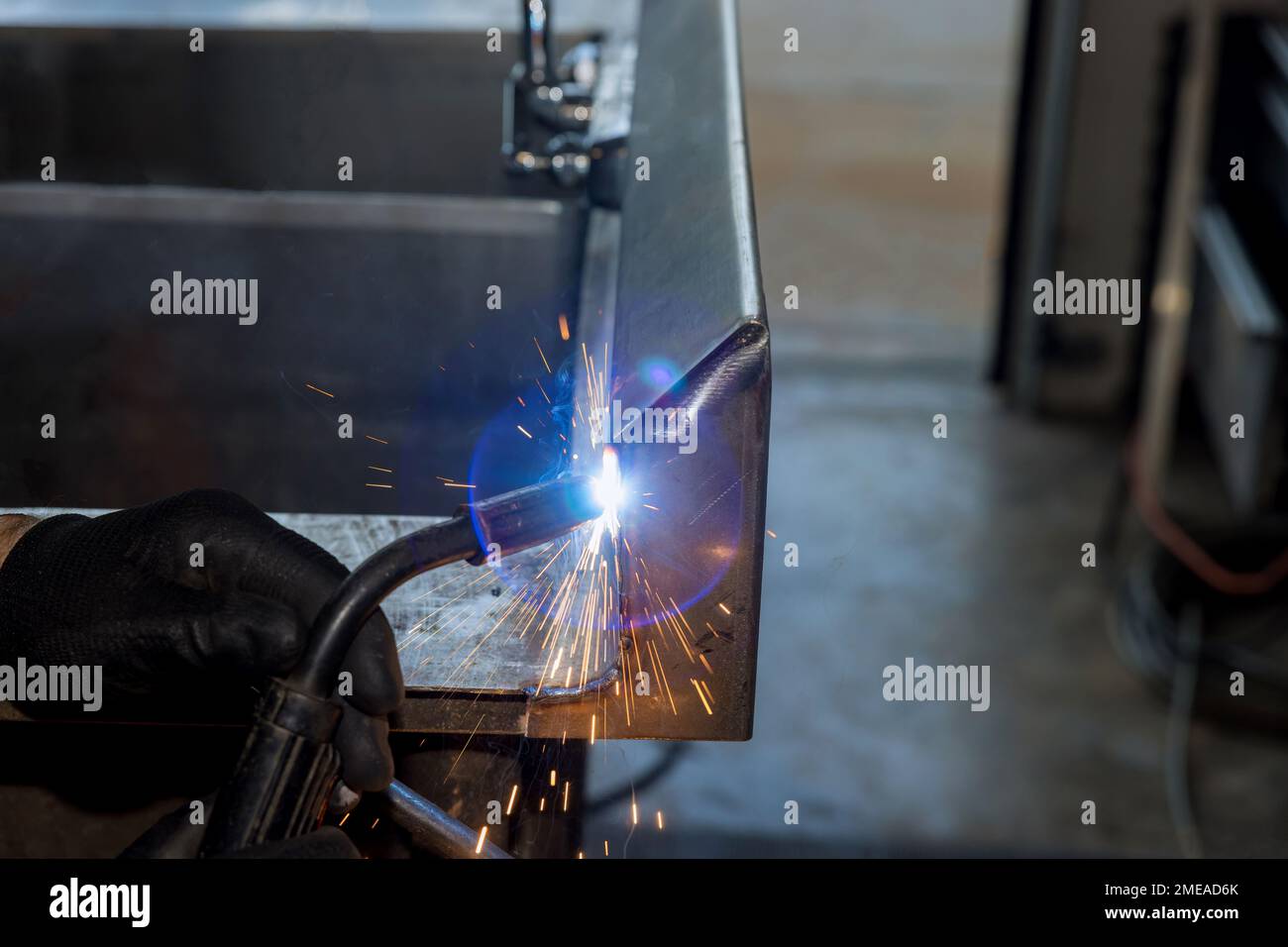 Worker is welding metal with sparkle using semiautomatic argon gas