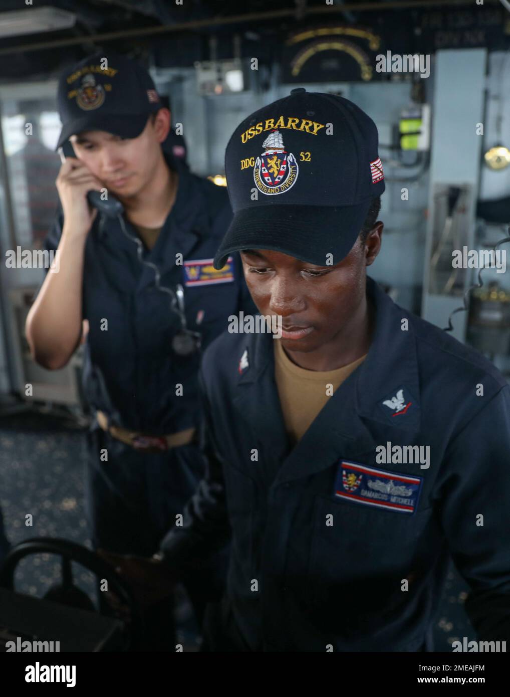 YOKOSUKA (Aug. 15, 2022) – Boatswain’s Mate 3rd Class Damarcus Mitchell, from Tampa Bay, Florida, pilots Arleigh Burke-class guided-missile destroyer USS Barry (DDG 52) with Lt. j.g. Thomas Barr, from Chula Vista, California, by his side Aug. 15 in waters off the coast of Yokosuka. Barry is assigned to Commander, Task Force 71/Destroyer Squadron (DESRON) 15, the Navy’s largest forward-deployed DESRON and the U.S. 7th Fleet’s principal surface force. Stock Photo
