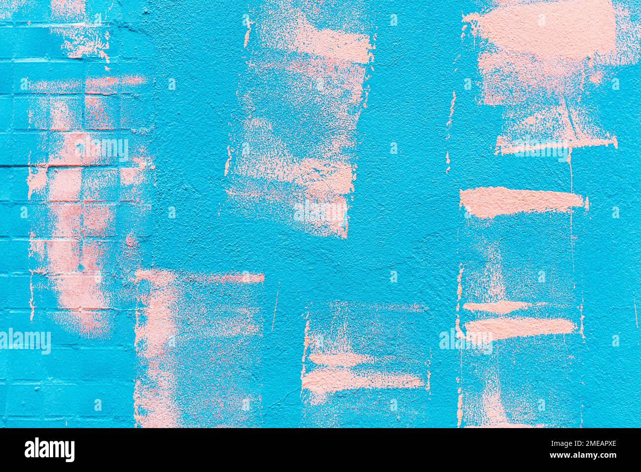 pink paint roller strokes on painted blue stucco wall Stock Photo