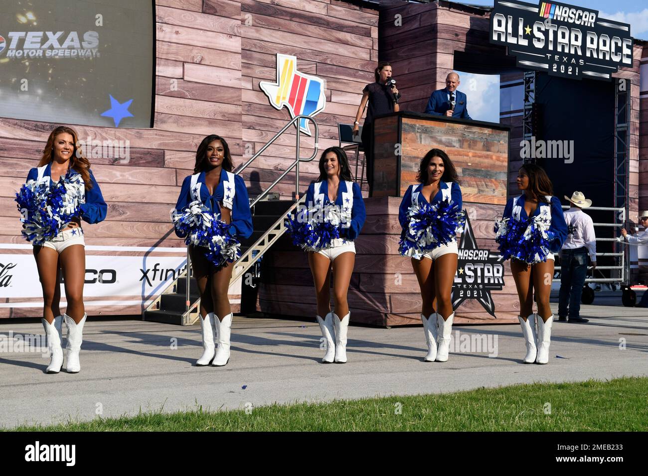 The Dallas Cowboys Cheerleaders perform by the All-Star stage as FOX  broadcast personalities Jamie Little, left rear, and Adam Alexander, right  rear, report during the NASCAR Cup Series All-Star auto race at