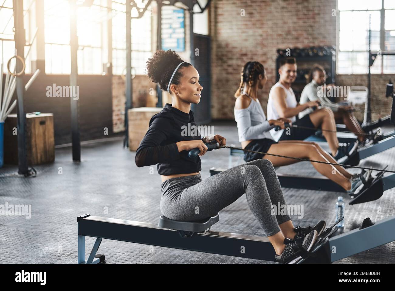 Rowing their way right towards their fitness goals. a young woman working out with a rowing machine in the gym. Stock Photo