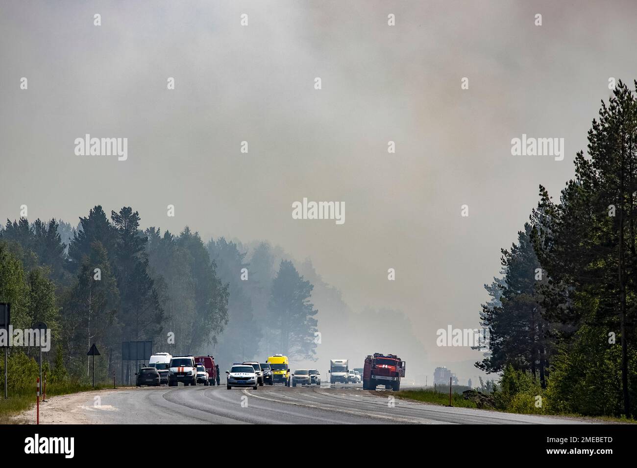 Cars drive through smoke away from a forest fire about 18 km 11.3