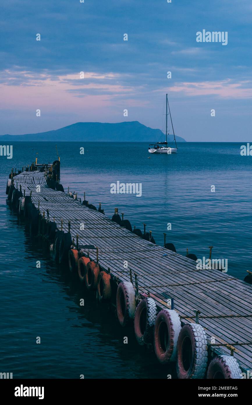 Old wooden fishing pier goes into the sea on sunset in spring. Resort city Novyi Svet, Crimea Stock Photo