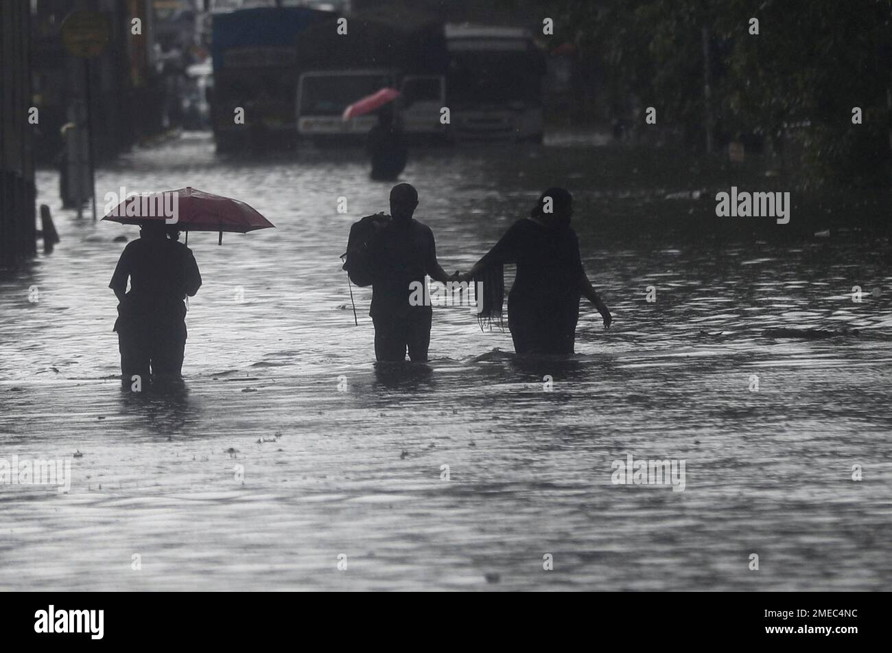 People walk through a flooded street during heavy rains in Mumbai ...