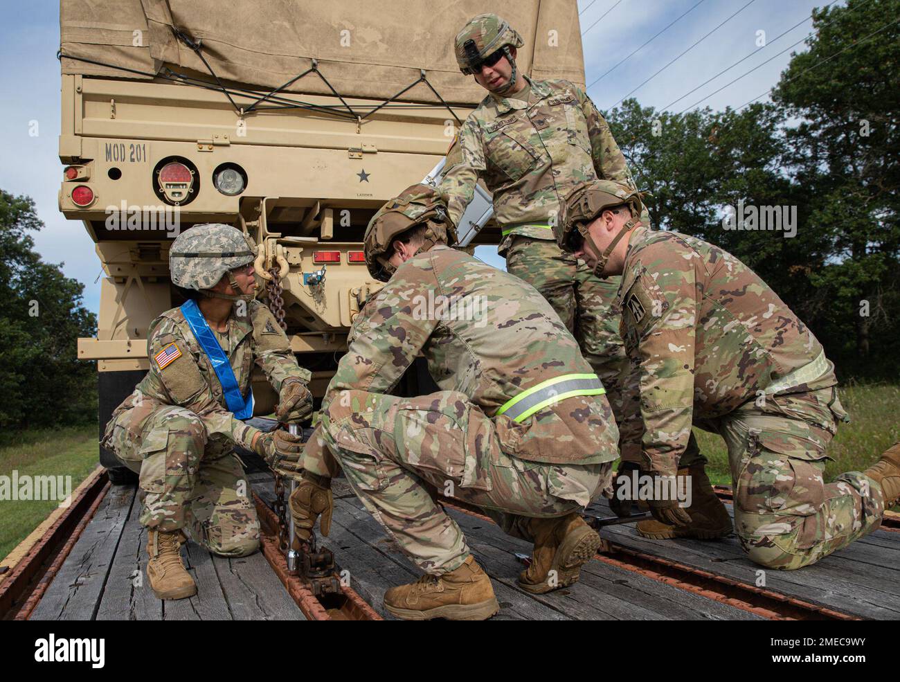 U.S. Army Soldiers, attending a Unit Movement Officer's (UMO) course, work  as a team to ensure a Light Medium Tactical Vehicle (LMTV) is chained down  to a rail car on Fort McCoy,