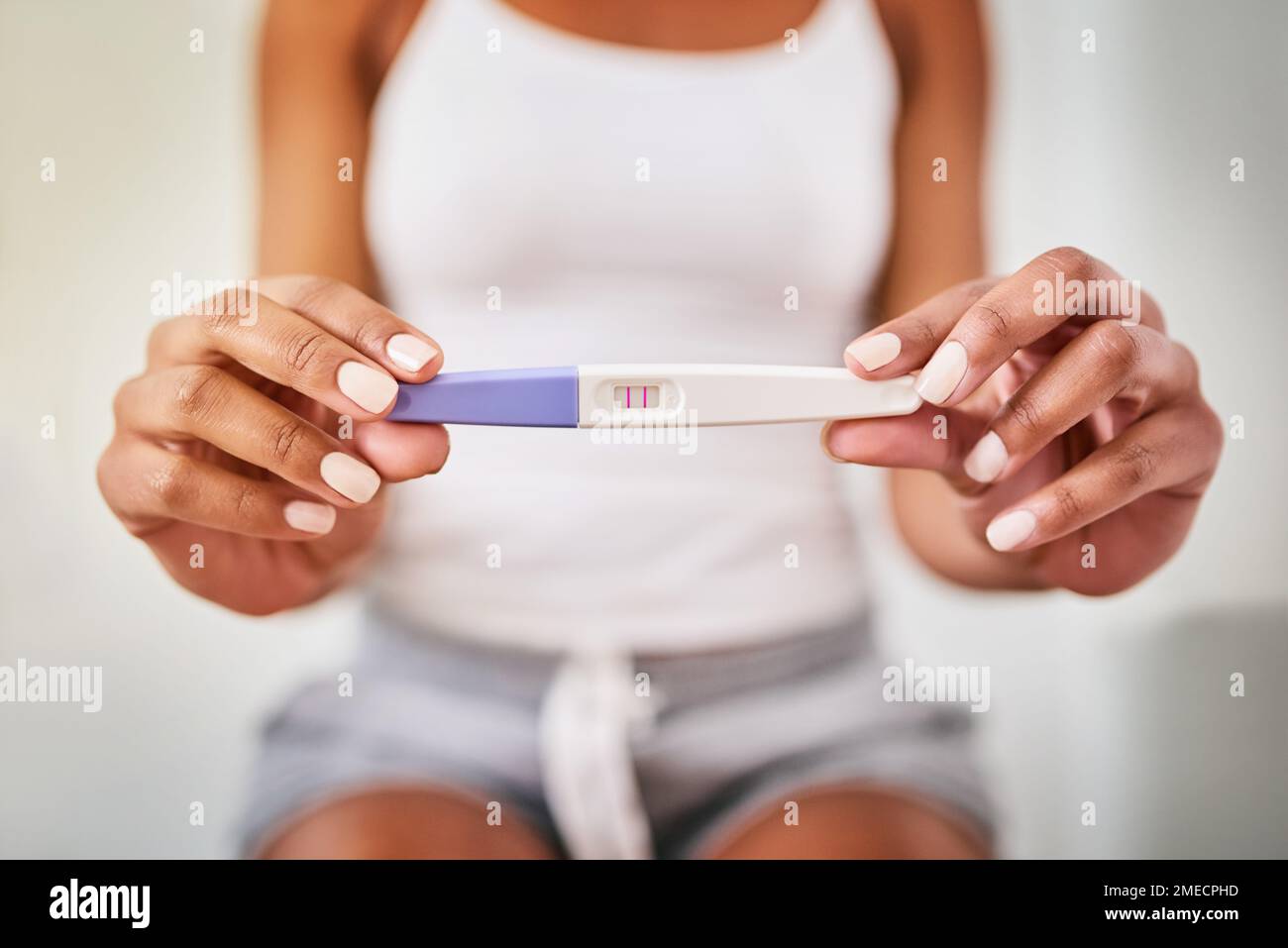 Someones about to be a mom. a woman taking a pregnancy test while sitting on the toilet. Stock Photo