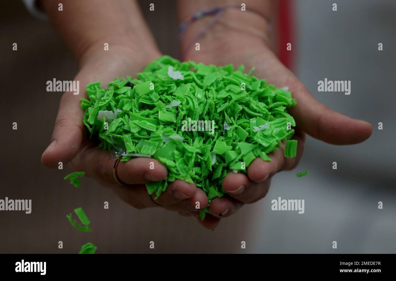 A worker shows shredded bottle caps that will be transformed into 