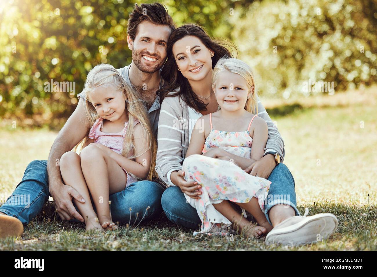 Family, garden and portrait of parents, children and happy people on park grass in sunshine. Kids, mom and dad smile with love in nature, holiday and Stock Photo