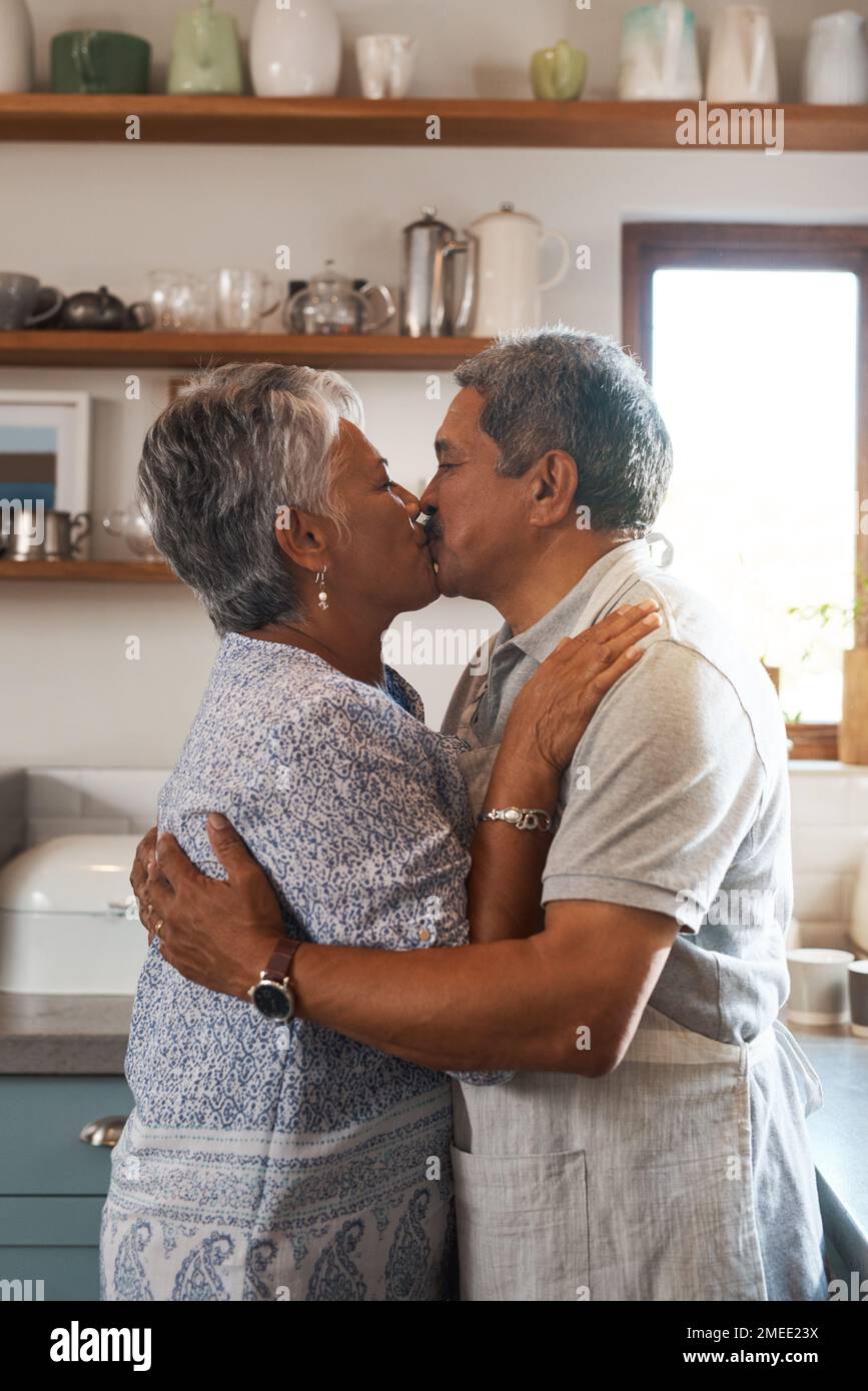 Nothing is more beautiful than eternal love. a mature couple kissing in the kitchen. Stock Photo