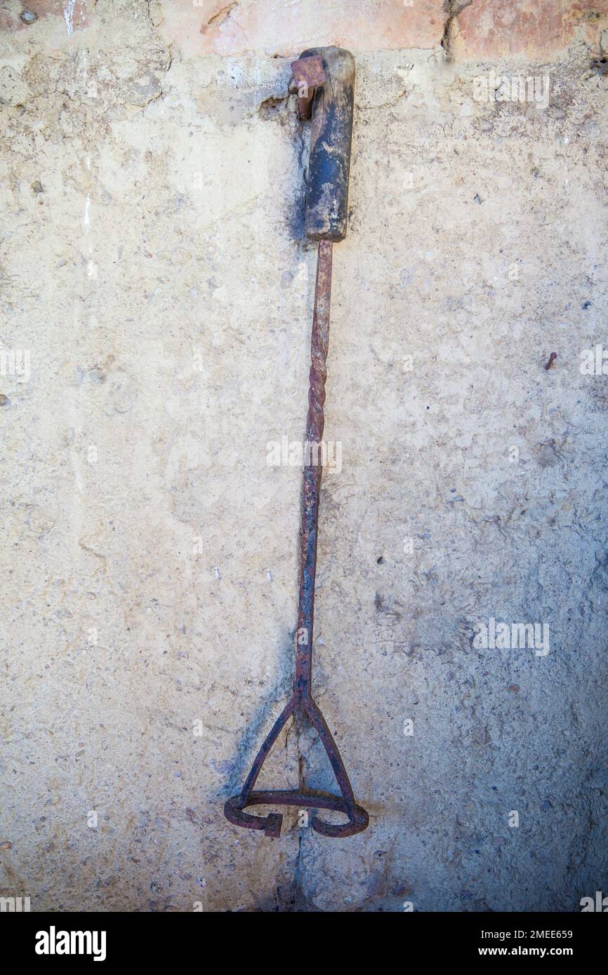 Branding iron for cattle hanging from a nail on the adobe wall of an old stable. Selective focus Stock Photo