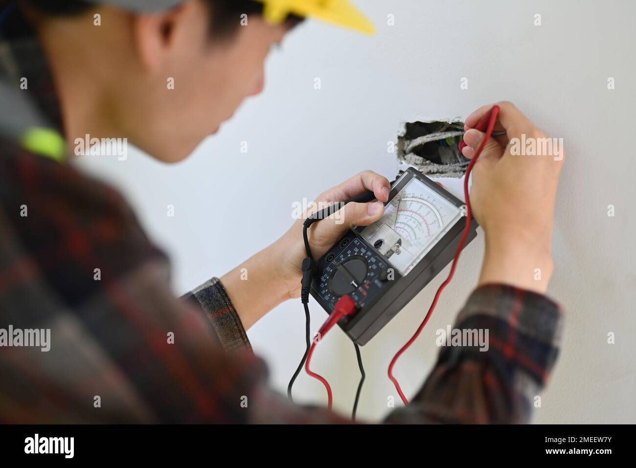 Over shoulder view of electrician installer using a multimeter to test