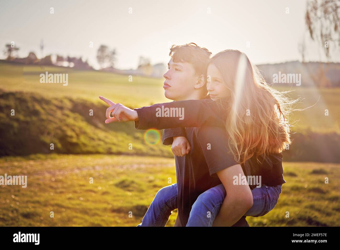 Boy and girl, brother and sister, siblings, interacting on a sunny day, during sunset in nature. Beautiful children sharing family moments outdoors Stock Photo