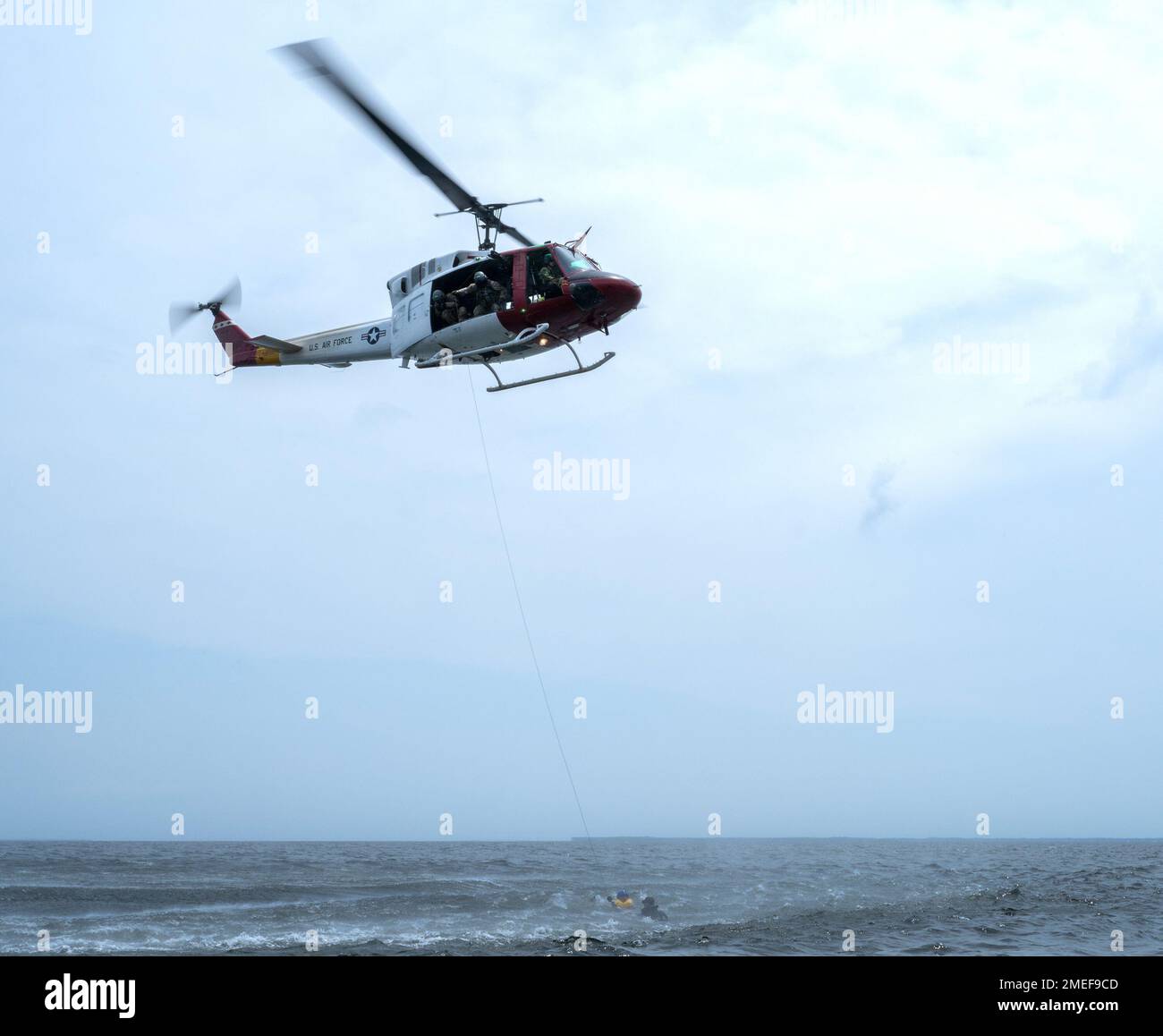 A 413th Flight Test Squadron UH-1 Huey hovers waiting to hoist a 492nd Special Operations Wing Airman out of the waters near Eglin Air Force Base, Florida Aug. 16.  The 413th FLTS, the Air Force’s only rotary wing developmental test unit, provided an extra bit of realism to the survival, evasion, resistance and escape training letting the Airmen experience the feeling of a real water rescue. (U.S. Air Force photo/Samuel King Jr.) Stock Photo